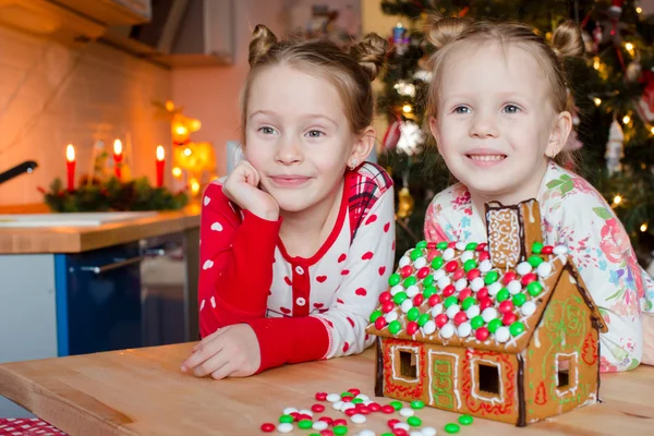 Little happy girls decorating gingerbread house for Christmas — Stock Photo, Image