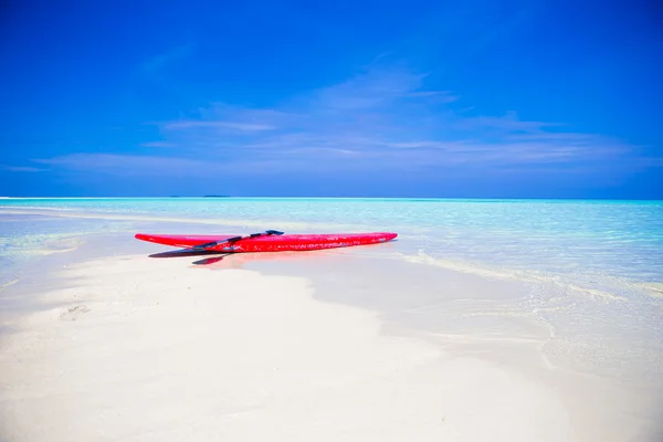 Rotes Surfbrett am weißen Sandstrand mit türkisfarbenem Wasser — Stockfoto