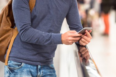 Uçuş bekliyor havaalanında cep telefonu tutan sırt çantası ile genç adam