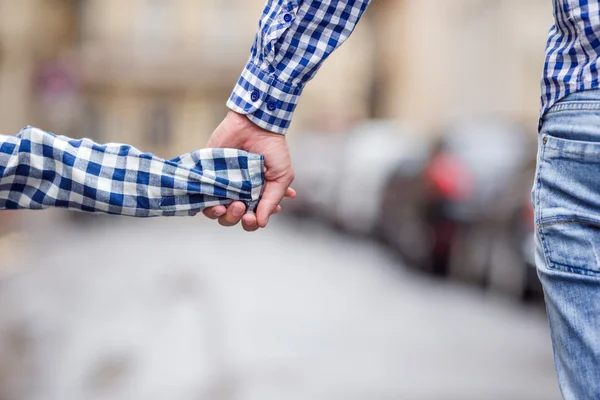 Hands of man and child holding together on street at european city — Stock Photo, Image