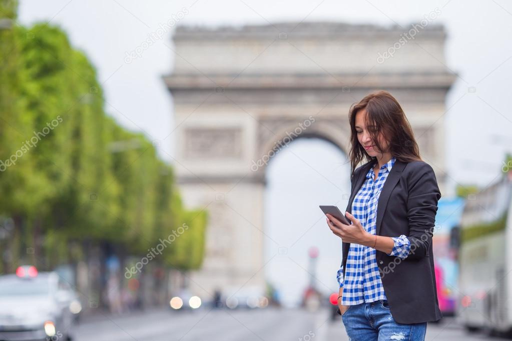 Beautiful woman holding a phone on the Champs Elysees in Paris