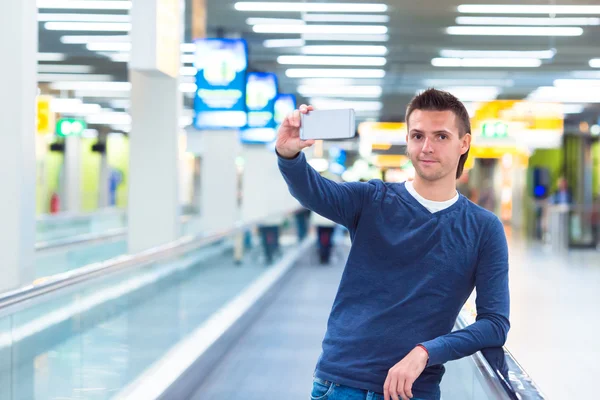 Junger Mann macht Selfie mit Handy am Flughafen — Stockfoto