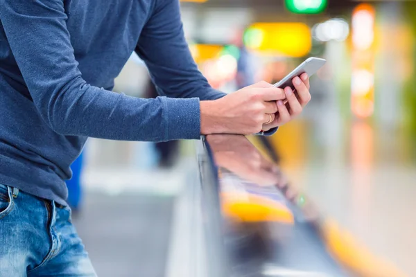 Man med ryggsäck håller mobilen på flygplatsen väntar på flyget — Stockfoto