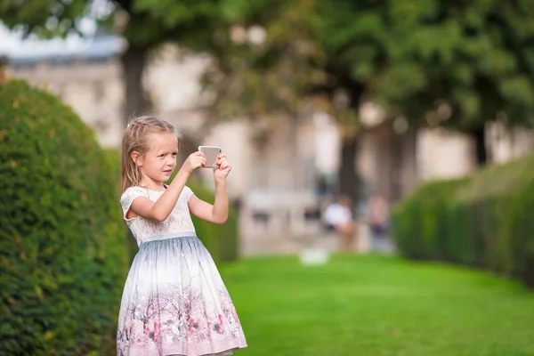 Entzückendes kleines Mädchen mit Handy in Paris während der Sommerferien — Stockfoto