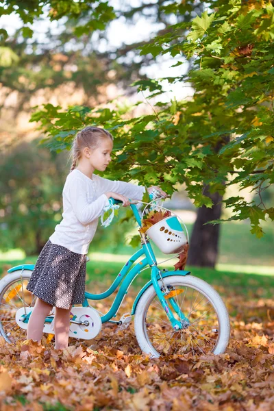 Adorable girl riding a bike at beautiful autumn day outdoors — Stock Photo, Image