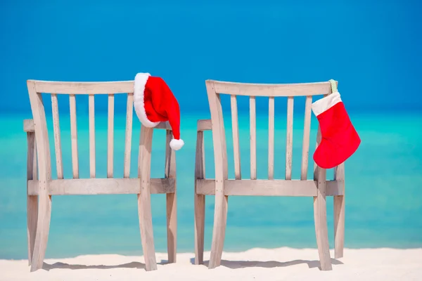 Duas espreguiçadeiras com chapéus vermelhos de Santa na praia tropical com areia branca e água azul-turquesa — Fotografia de Stock