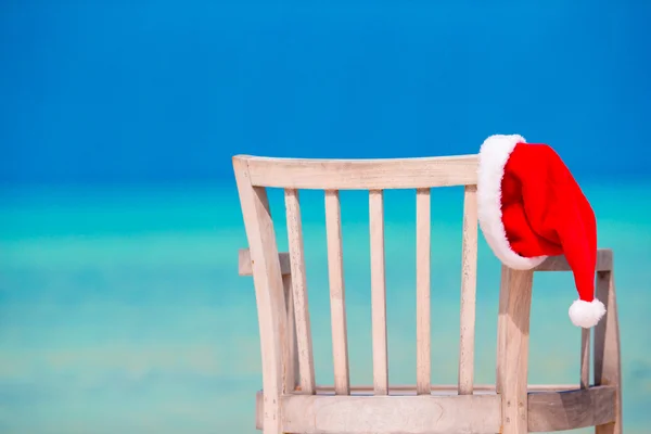 Red Santa hat on chair longue at tropical white beach — стоковое фото