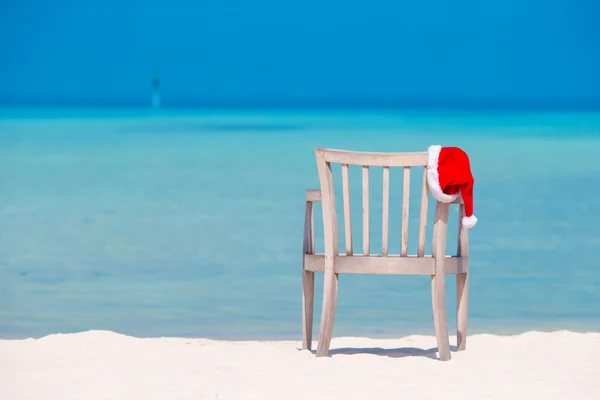 Concepto de Navidad. Sombrero rojo de santa en la playa tropical blanca . — Foto de Stock