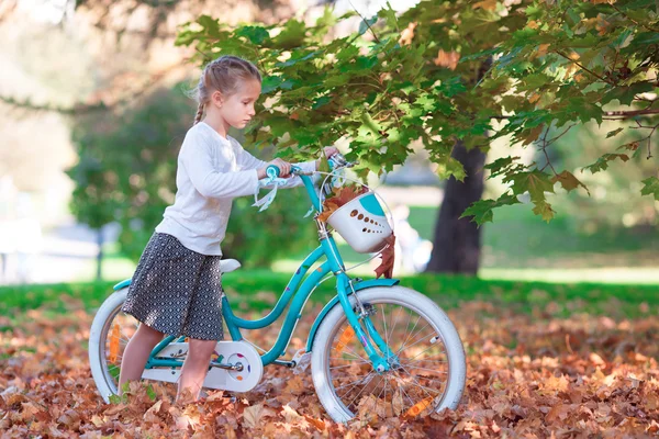 Adorable girl riding a bike at warm autumn day outdoors — Stock Photo, Image