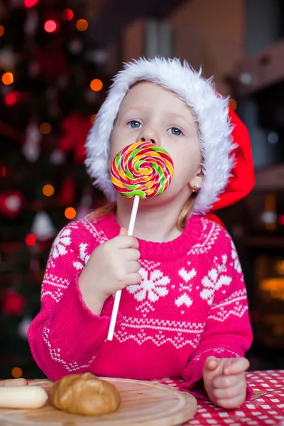 Entzückendes Mädchen, das an Heiligabend Weihnachtsplätzchen backt. Weihnachtsbaum und Lichter im Hintergrund. — Stockfoto
