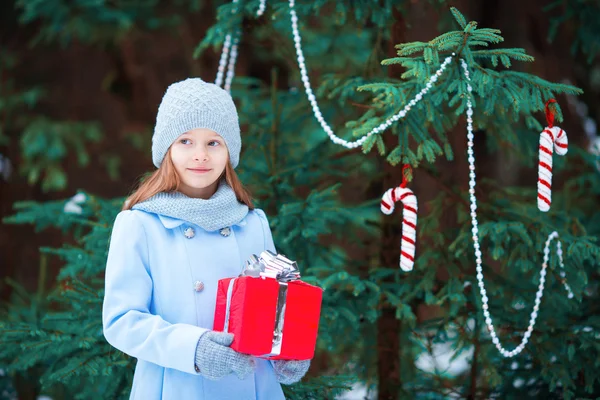 Adorable little girl with Christmas box gift in winter outdoors on Xmas eve — Stock Photo, Image