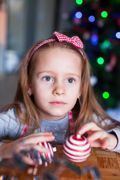 Schattig meisje kerstkoekjes bakken op Xmas eve. Kerstboom en lichten op achtergrond. — Stockfoto