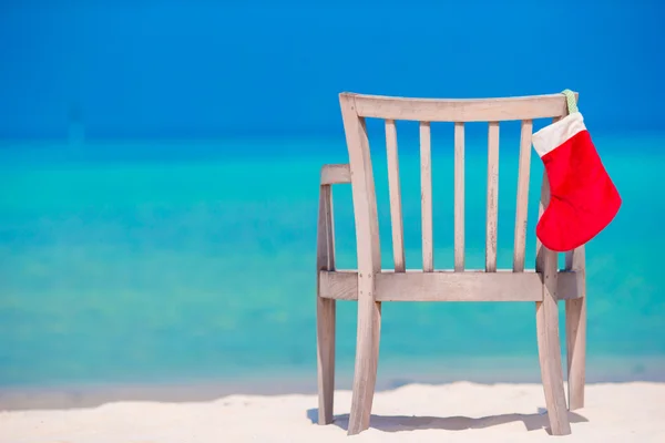 Red Christmas stocking op tropische witte strand. Kerstmis concept. — Stockfoto