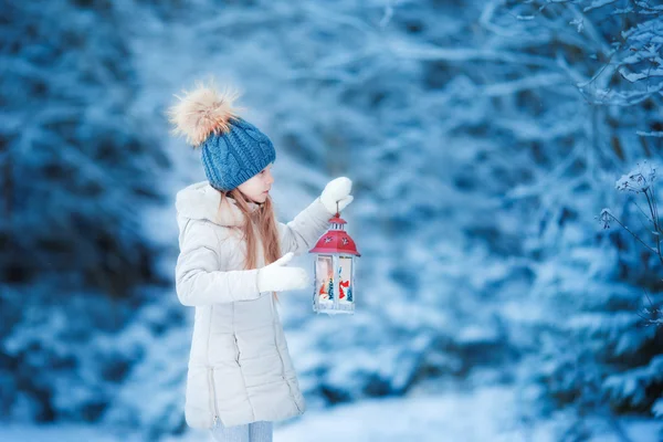 Adorable niña con linterna y vela en invierno en Navidad al aire libre —  Fotos de Stock
