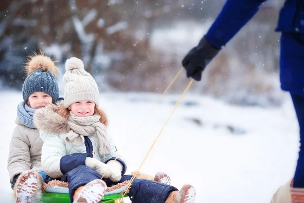 Las niñas disfrutan de un paseo en trineo. Un trineo infantil. Los niños juegan al aire libre en nieve. Vacaciones familiares en Nochebuena al aire libre —  Fotos de Stock