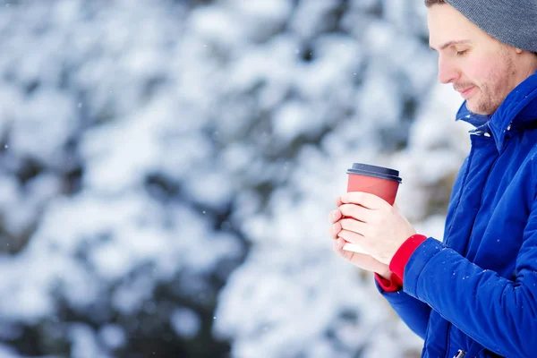 Ung kaukasiska man dricka kaffe i frysta vinter dag utomhus — Stockfoto