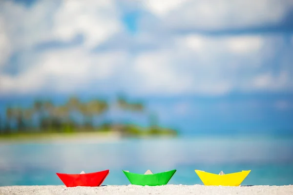 Conceito de negócio para desafio e movimento: três barcos de papel coloridos em fundo azul-turquesa oceano. Barcos de papel verde, vermelho e amarelo na praia branca tropical ao ar livre — Fotografia de Stock