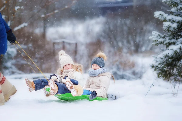 Alle bambine piace fare un giro in slitta. Slitta infantile. I bambini giocano all'aperto nella neve. Vacanza in famiglia la vigilia di Natale all'aperto — Foto Stock