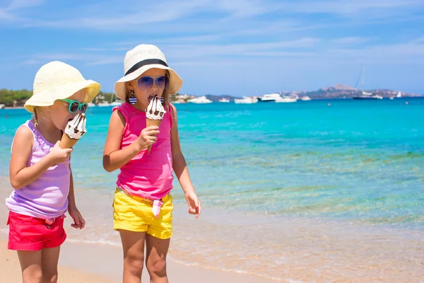 Счастливые маленькие девочки едят мороженое на летнем пляже. Люди, дети, друзья и концепция дружбы — стоковое фото
