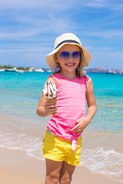 Lycklig liten flicka äter glass över sommaren beach bakgrund. — Stockfoto