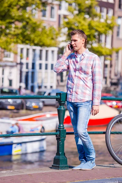 Ung man prata via telefon i Amsterdam bridge — Stockfoto