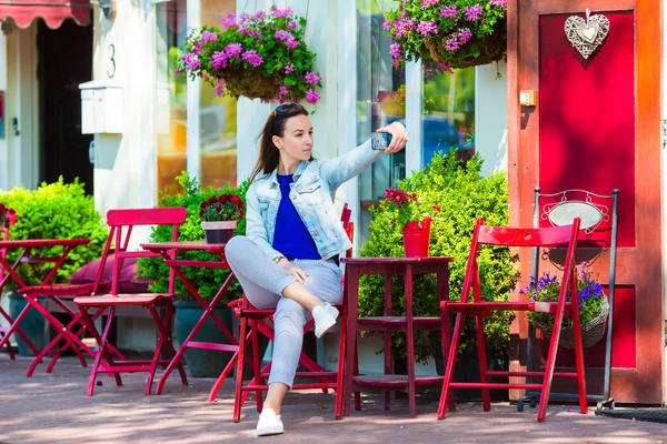 Mujer joven tomando autorretrato en la cafetería al aire libre en la ciudad europea —  Fotos de Stock