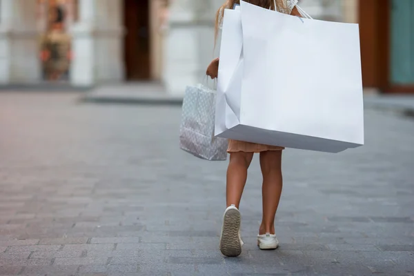 Kleines Mädchen läuft mit Einkaufstaschen im Freien in der europäischen Stadt — Stockfoto