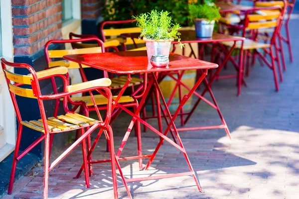 Tavoli e sedie rosse in un caffè sul marciapiede della città europea — Foto Stock