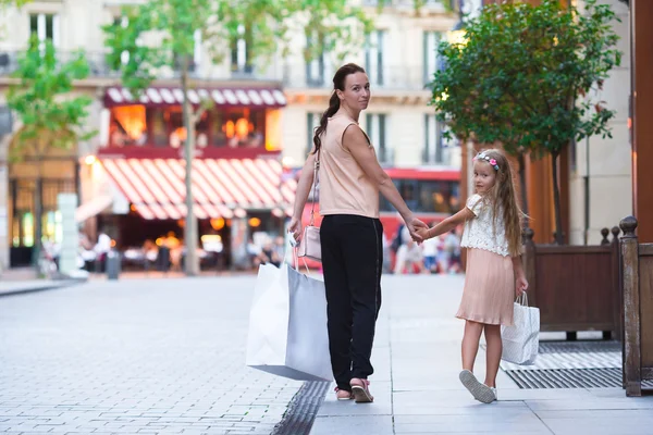 Adorable niña y madre feliz caminando con bolsas de compras en París al aire libre — Foto de Stock