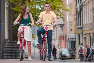 Amsterdam 'ın eski sokaklarında bisiklete binen mutlu beyaz bir çift.