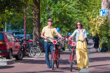 Amsterdam 'ın eski sokaklarında bisiklete binen mutlu beyaz bir çift.