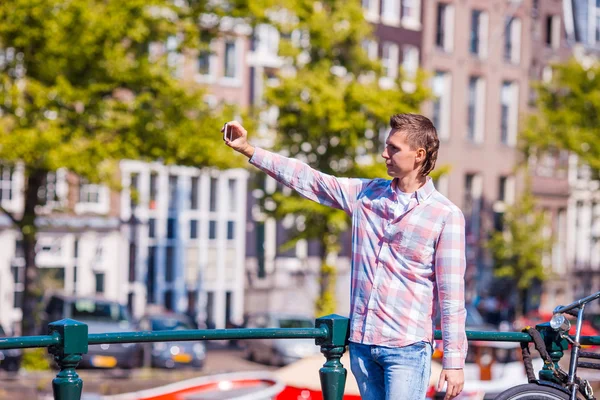Jovem tomando auto-retrato na cidade europeia ao ar livre. Jovem adulto segurando câmera smartphone para tirar uma foto de si mesma durante suas férias de verão em Amsterdã — Fotografia de Stock