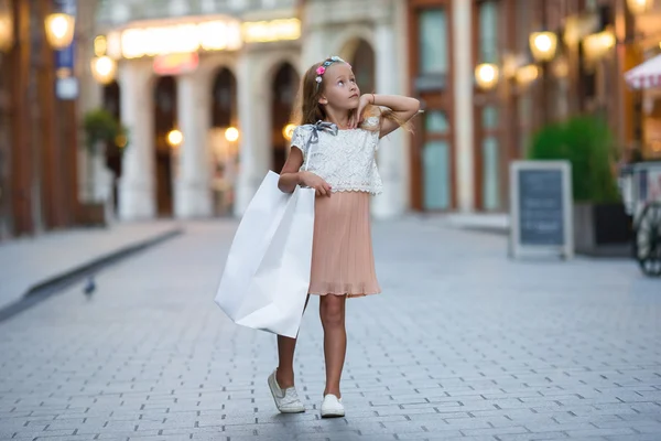 Adorable niña caminando con bolsas de compras en París al aire libre —  Fotos de Stock