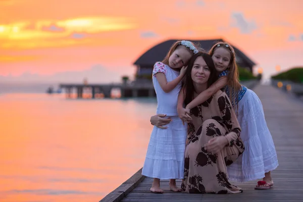 Jovem mãe e duas suas meninas em férias exóticas no pôr do sol — Fotografia de Stock