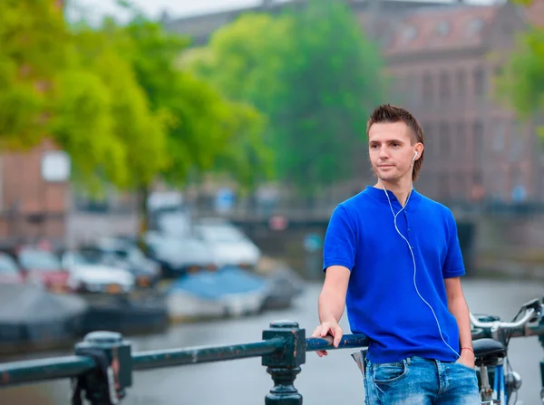 Joven hombre feliz escuchando música fondo de canal en Amsterdam, Países Bajos —  Fotos de Stock