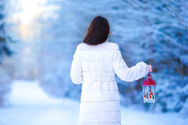 Young woman holding Christmas lantern outdoors on beautiful winter snow day — Stock Photo, Image