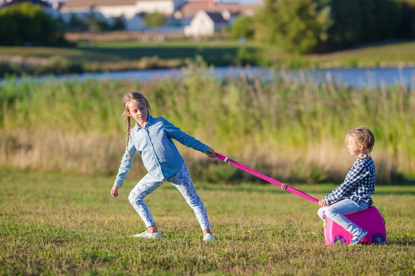 Due bambine che camminano con i bagagli pronti per viaggiare all'aperto — Foto Stock