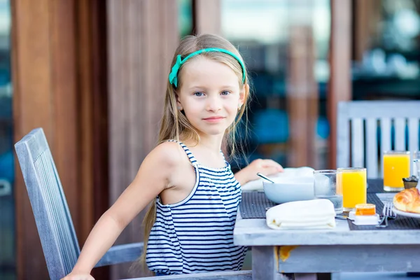 Urocza dziewczynka jedząca śniadanie w kawiarni na świeżym powietrzu — Zdjęcie stockowe