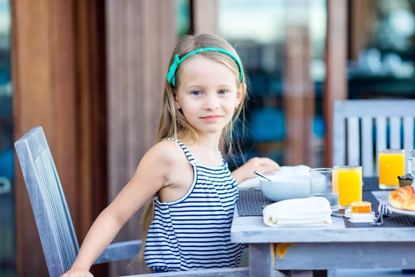 Liebenswertes kleines Mädchen frühstückt im Café im Freien — Stockfoto