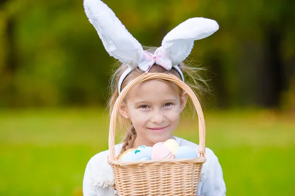 Portrait little girl with a basket full of Easter eggs on spring day outdoors — Stock Photo, Image