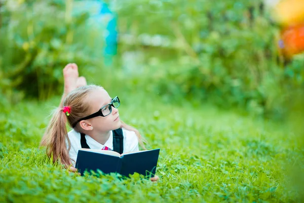 Adorável menina lendo um livro ao ar livre — Fotografia de Stock