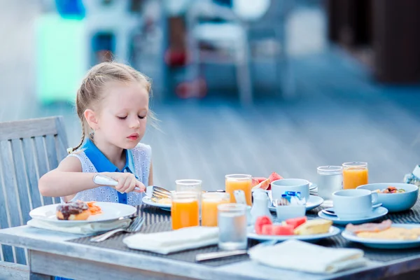 Liebenswertes kleines Mädchen frühstückt im Café im Freien — Stockfoto