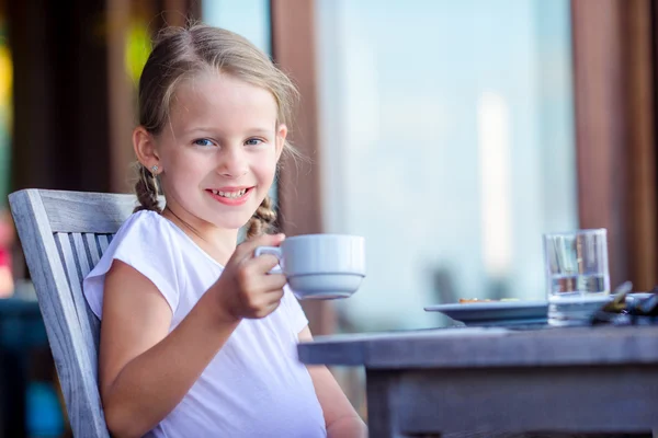 Entzückendes kleines Mädchen beim Frühstück mit heißem Kakao im Café — Stockfoto