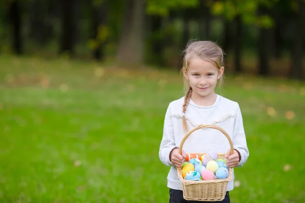 Menina adorável segurando uma cesta com ovos de Páscoa no dia de primavera ao ar livre — Fotografia de Stock