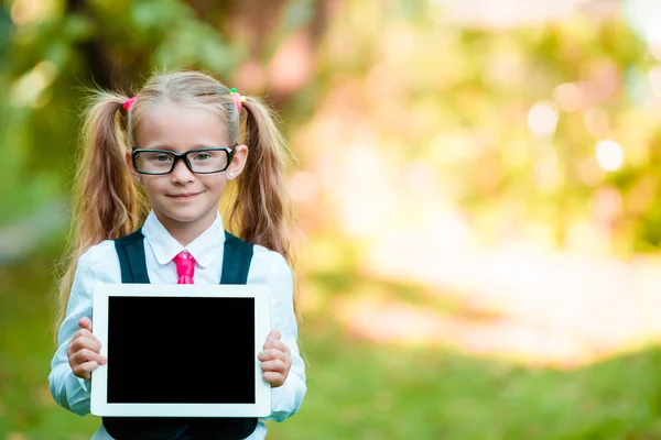 Bedårande liten flicka håller tablet Pc utomhus i soliga höstdag — Stockfoto