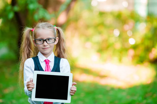 Bedårande liten flicka håller tablet Pc utomhus i soliga höstdag — Stockfoto