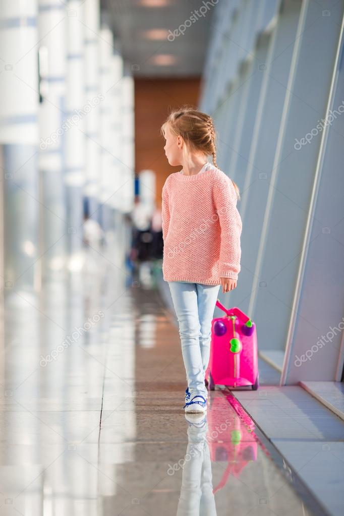 Adorable little girl with her luggage waiting the flight in airport