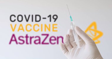 Covid-19 (Coronavirus) aşısı üreten şirketlerden biri olan AstraZeneca logosu önünde eldiven tutan bir el. Viyana, Avusturya - 11 Ocak 2021