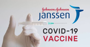 Eldivenli el şırıngası Janssen, Johnson ve Johnson logolarının yanında, Covid-19 (Coronavirus) aşısı geliştiren iki şirketin yanında duruyor. Viyana, Avusturya - 18 Ocak 2021