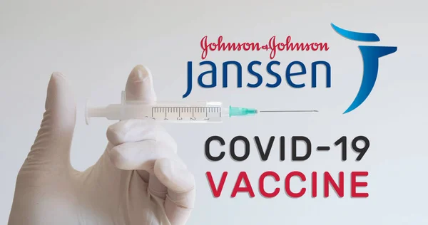 在研发Covid Coronavirus 疫苗的两家公司Janssen Johnson和Johnson Logos的旁边 手拿着手套拿着注射器 2021年1月18日 奥地利维也纳 图库图片